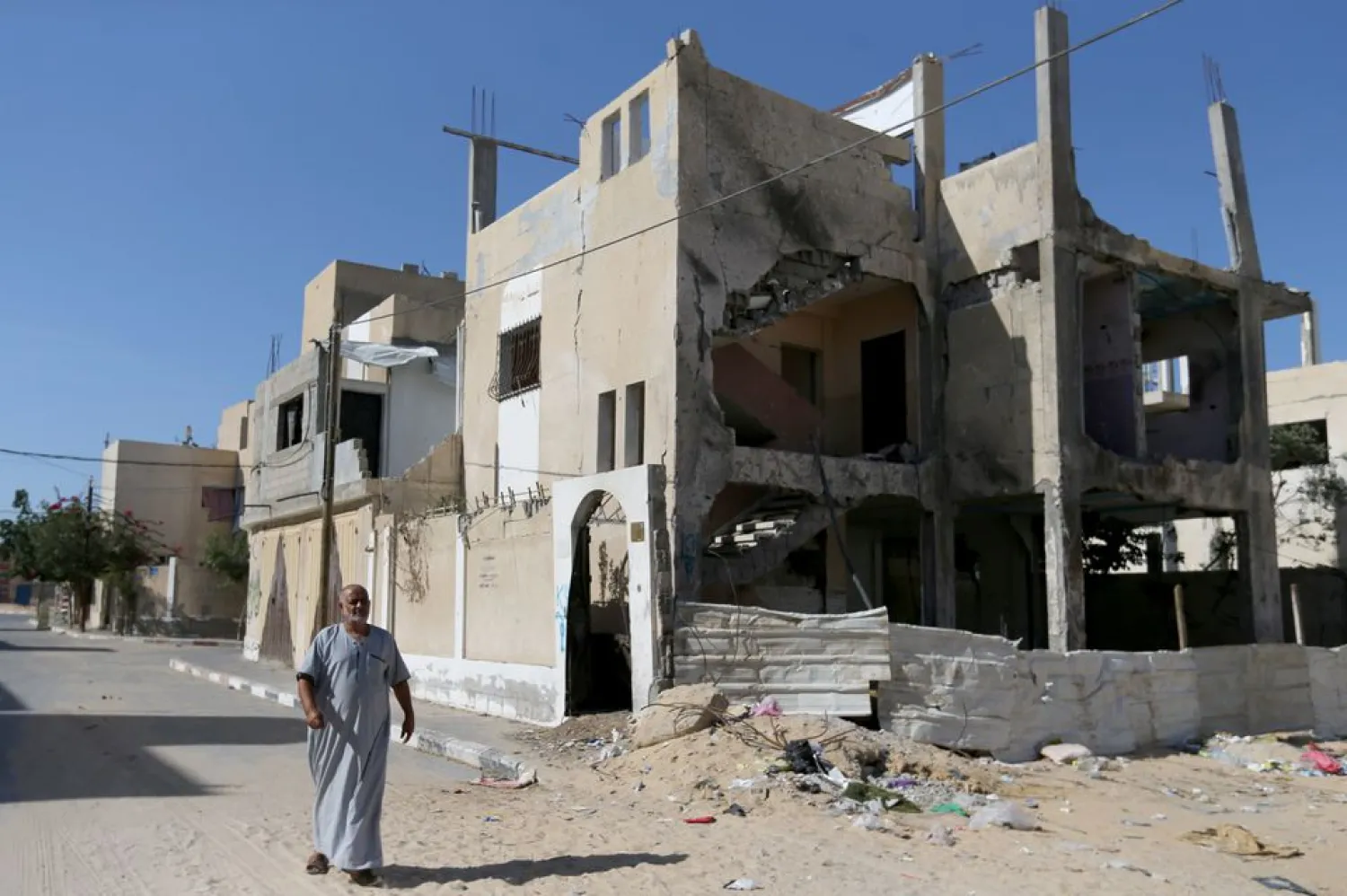 A Palestinian man walks outside a house that was damaged by Israeli strikes during Israel-Hamas fighting last May, in Khan Younis in southern Gaza Strip September 26, 2021. REUTERS/Ibraheem Abu Mustafa