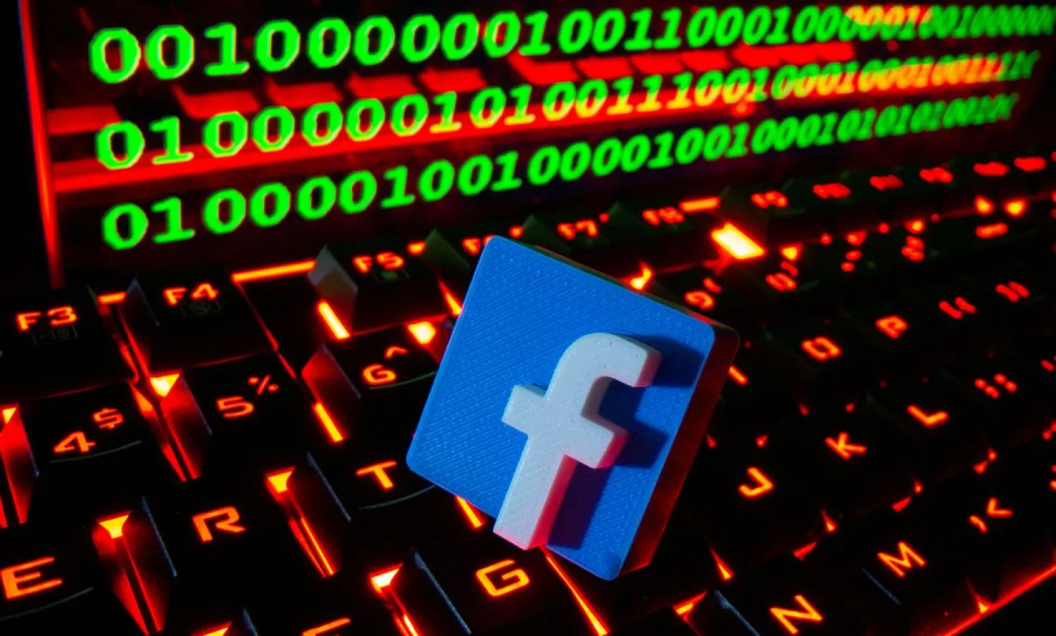 A 3D printed Facebook logo is pictured on a keyboard in front of binary code in this illustration taken September 24, 2021. (Reuters)