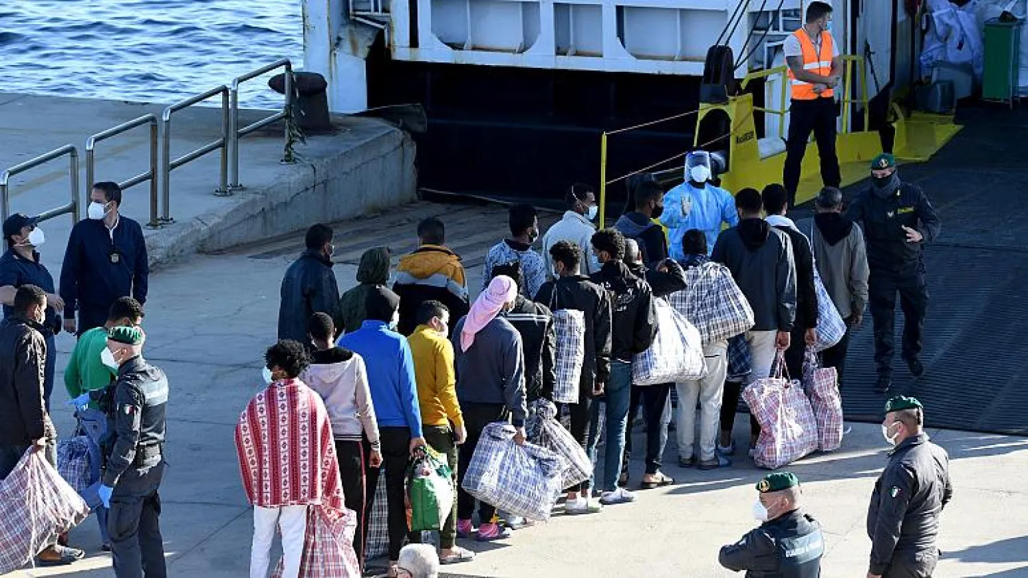 Migrants queue before boarding the GNV Azzurra ship after being transferred from the migrant center on the Sicilian island of Lampedusa, May 13, 2021. (AP Photo/Salvatore Cavalli)
