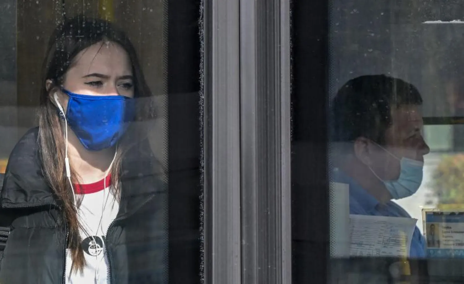 سيدة وسائق حافلة يرتديان قناعين للوجه في موسكو (أ.ف.ب)