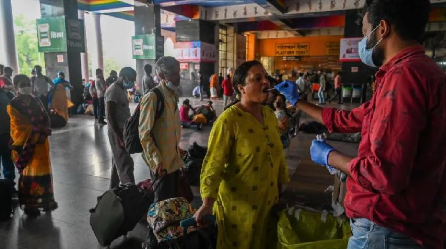 Yeni Delhi’deki bir tren istasyonunda bulunan bir kadın koronavirüs testinden geçiyor (AFP)