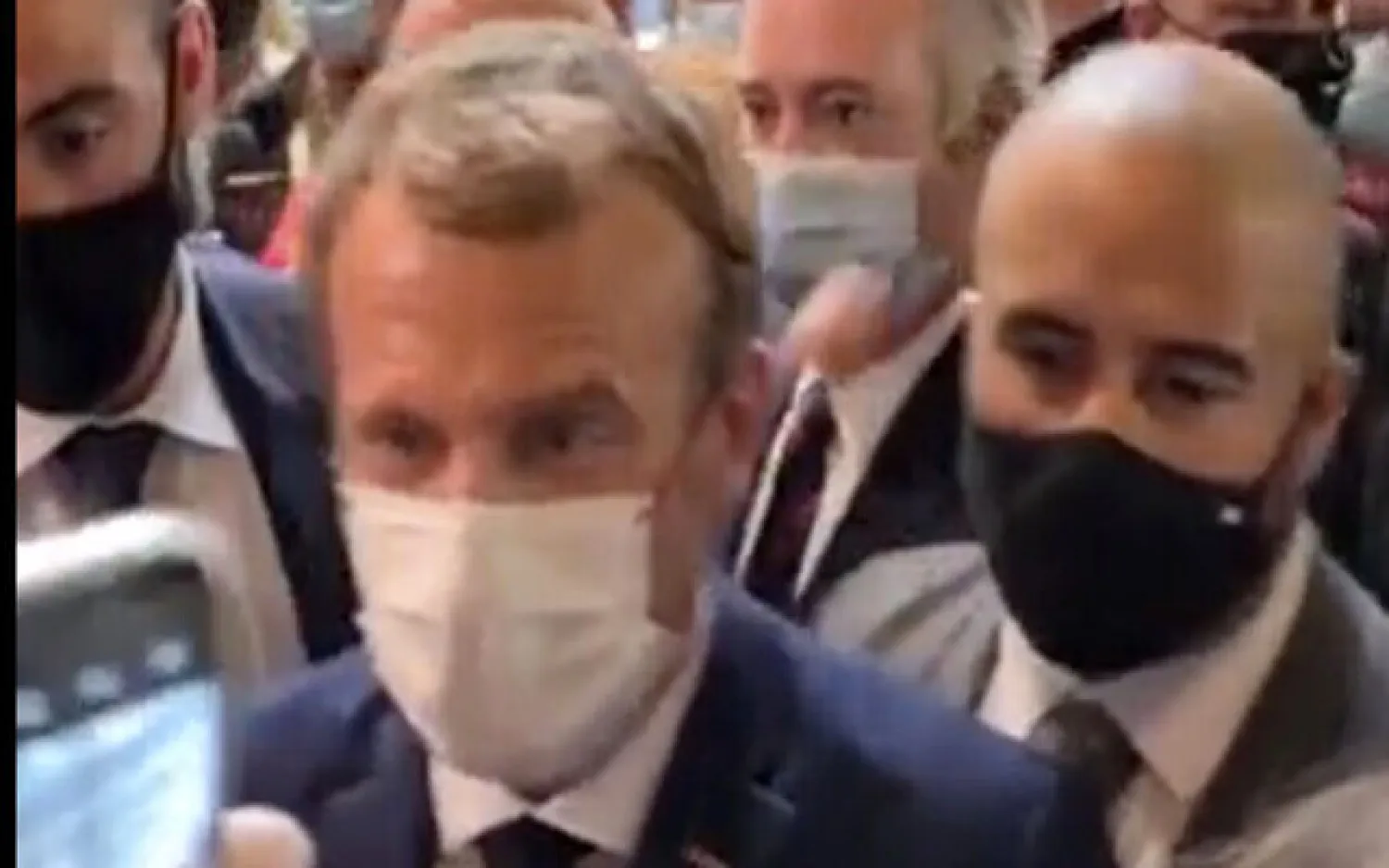 This image from video made available by Lyonmag.com shows an egg thrown toward French President Emmanuel Macron, left, to hit him on the shoulder as he walks through the restaurant trade fair in Lyon, France, September 27, 2021. (LYONMAG.COM via AP)
