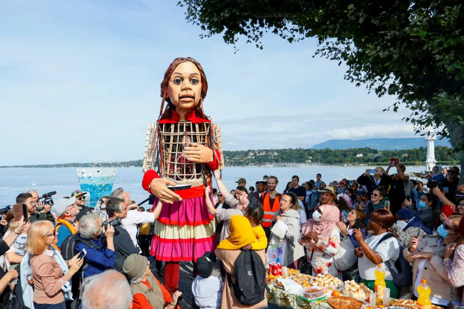 People look at Little Amal, a 3.5-meter-tall puppet depicting an unaccompanied Syrian refugee, in Bains des Paquis in Geneva, Switzerland, September 28, 2021. (Reuters)
