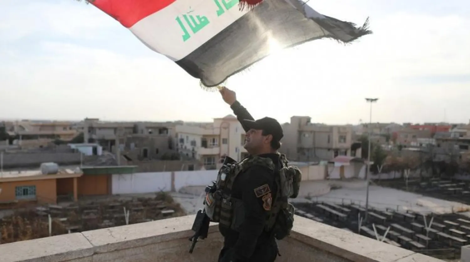 An Iraqi special forces soldier waves an Iraqi flag in Bartella, east of Mosul, Iraq. (Reuters)