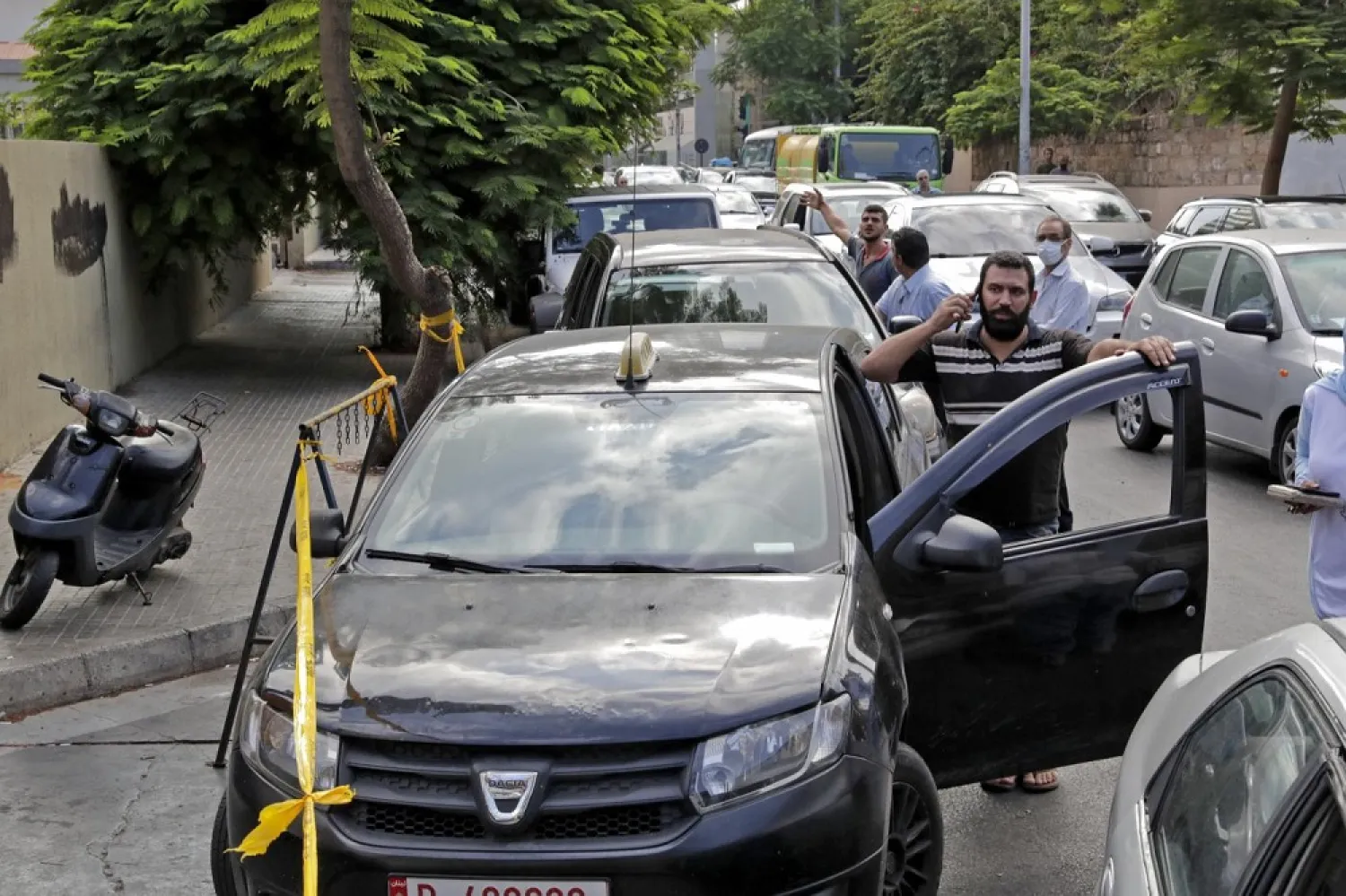 Lebanese wait in a queue outside a closed petrol station in Beirut's Hamra district on August 20, 2021. (AFP)