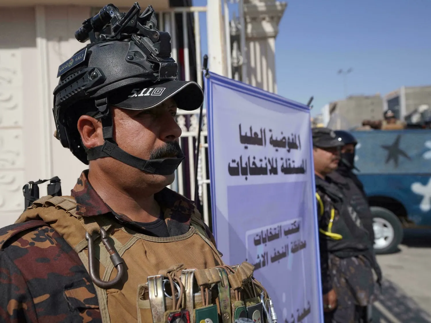 Iraqi security forces stand guard as officials of the Independent High Electoral Commission conduct a draw to select candidates in the upcoming parliamentary election, in the central city of Najaf on July 7. (AFP)