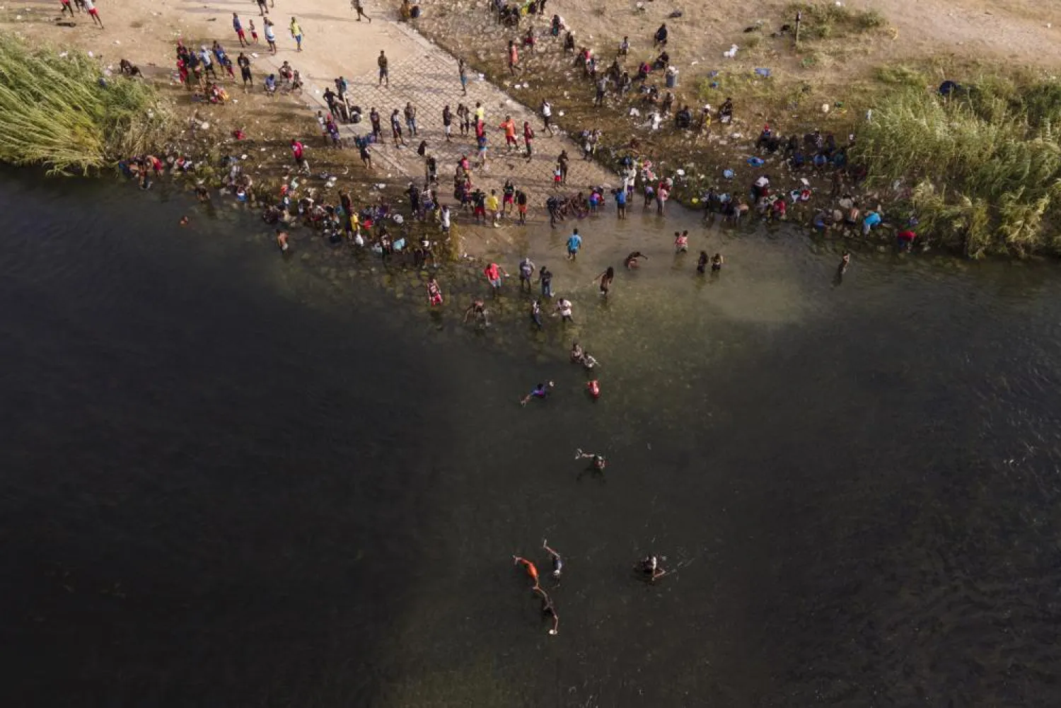 Migrants, many from Haiti, are seen wading between the US and Mexico on the Rio Grande, Tuesday, Sept. 21, 2021, in Del Rio, Texas. (AP Photo/Julio Cortez)
