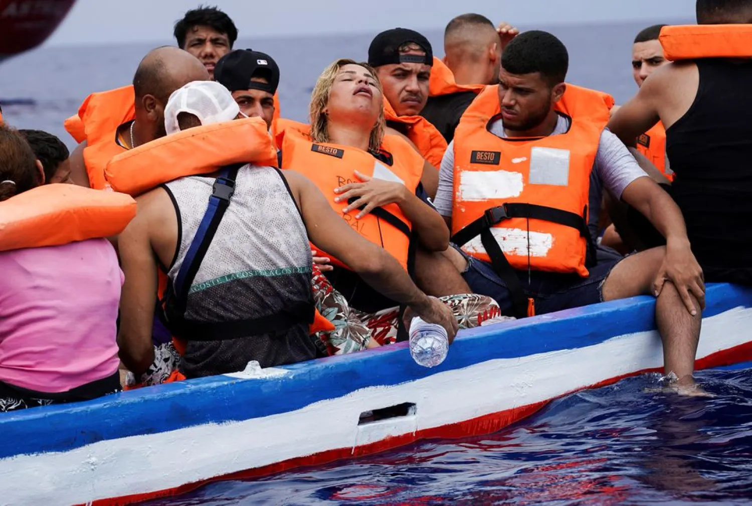 A pregnant woman reacts on board a wooden boat as they wait for the Italian Guardia Costiera near the island of Lampedusa, in the Mediterranean Sea, September 1, 2021. REUTERS/Juan Medina