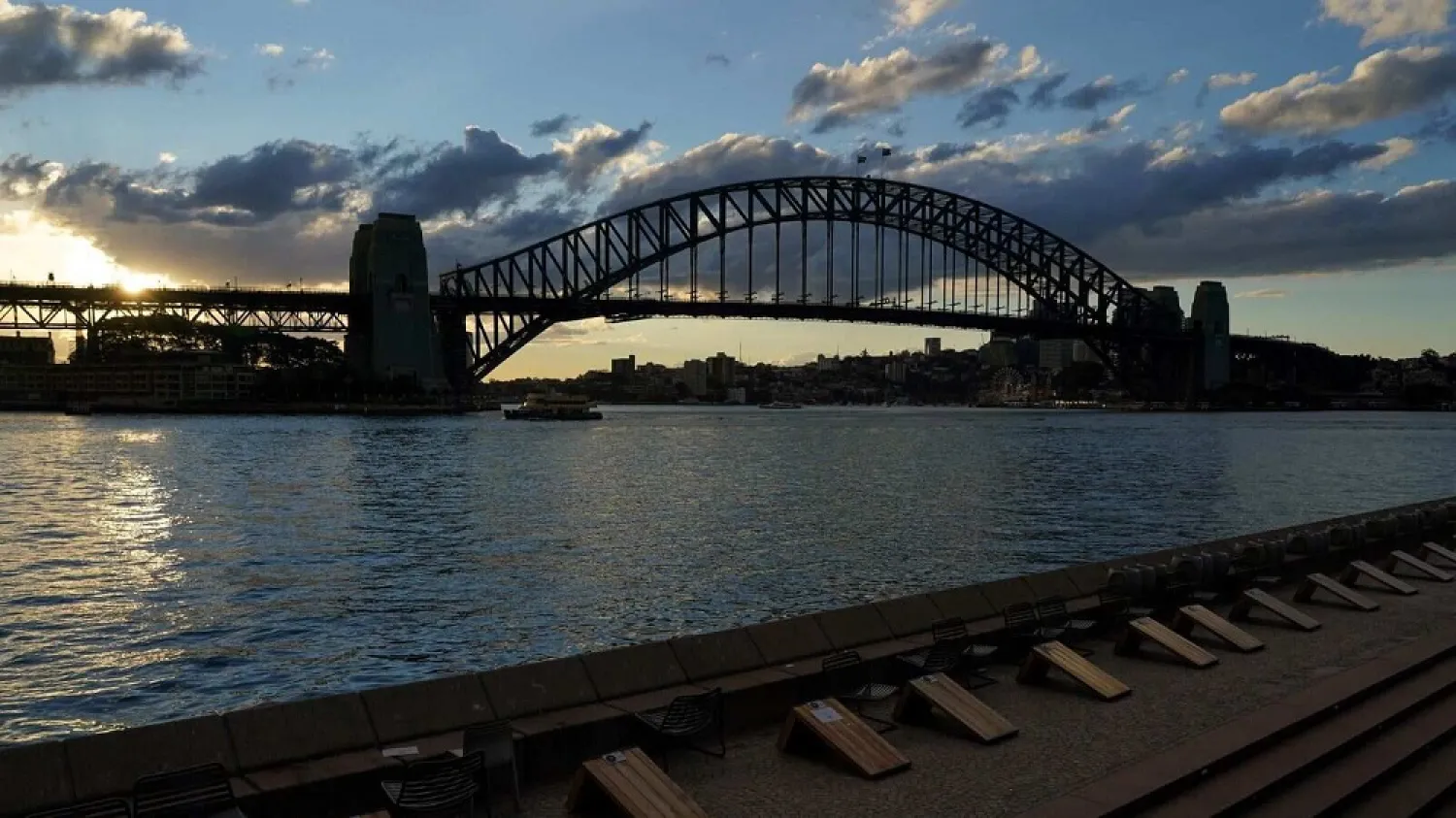 Harbor waterfront seating is devoid of people at sunset in front of the Sydney Harbor Bridge during a lockdown. (Reuters)