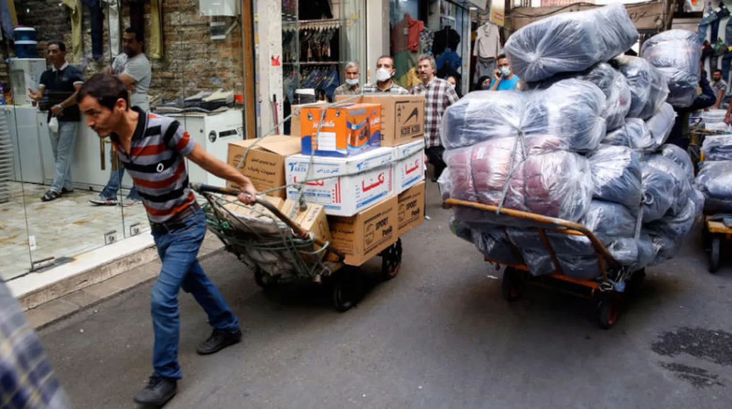 عمال إيرانيون في البازار الكبير بطهران أمس (إ.ب.أ)