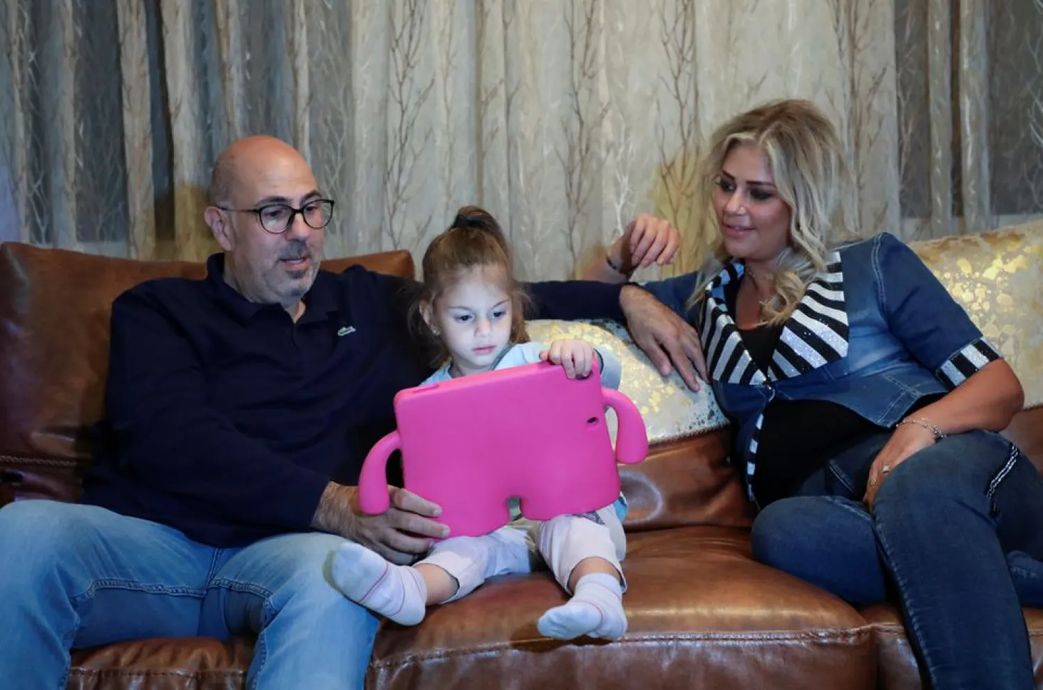 Ralph Khoury, 44, sits with his wife and one of his two daughters, during an interview with Reuters at his home in Qornet El Hamra, Lebanon, September 24, 2021. (Reuters)