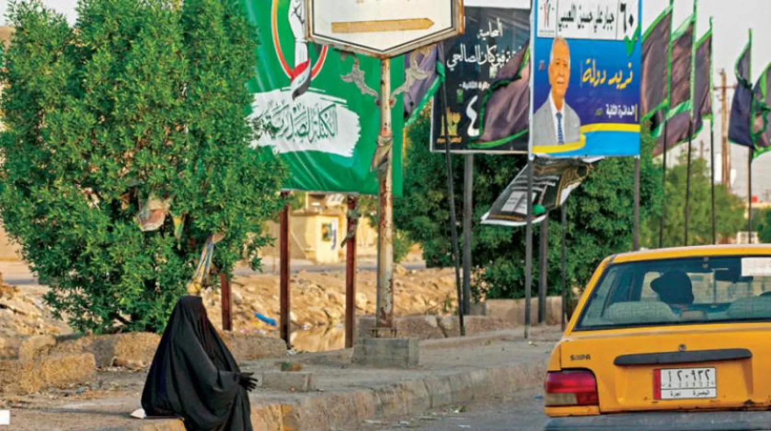 An Iraqi woman near electoral campaign posters in Basra (AFP)
