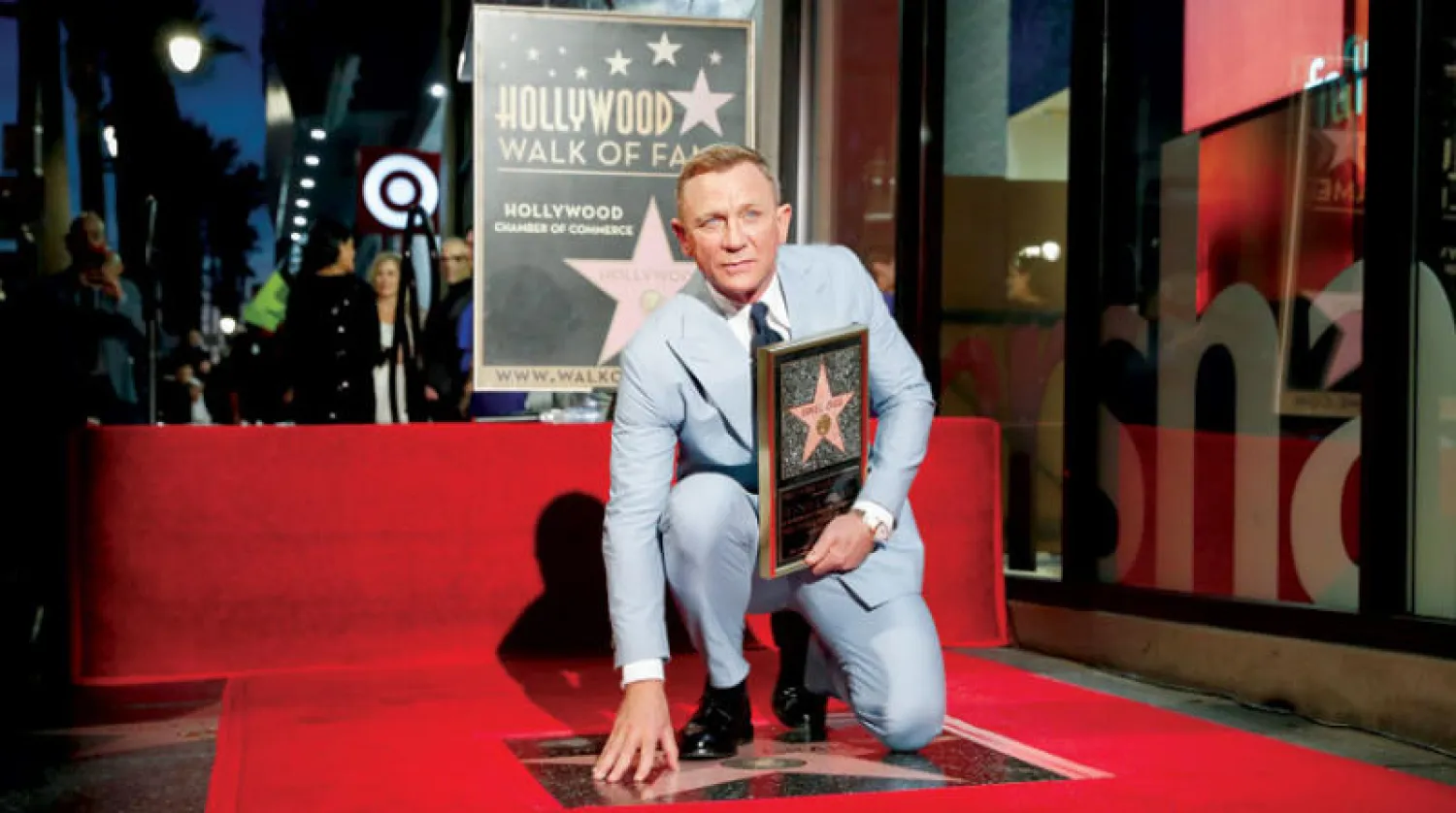 كريغ يجلس على نجمه الجديد في ممشى المشاهير (إ.ب.أ)