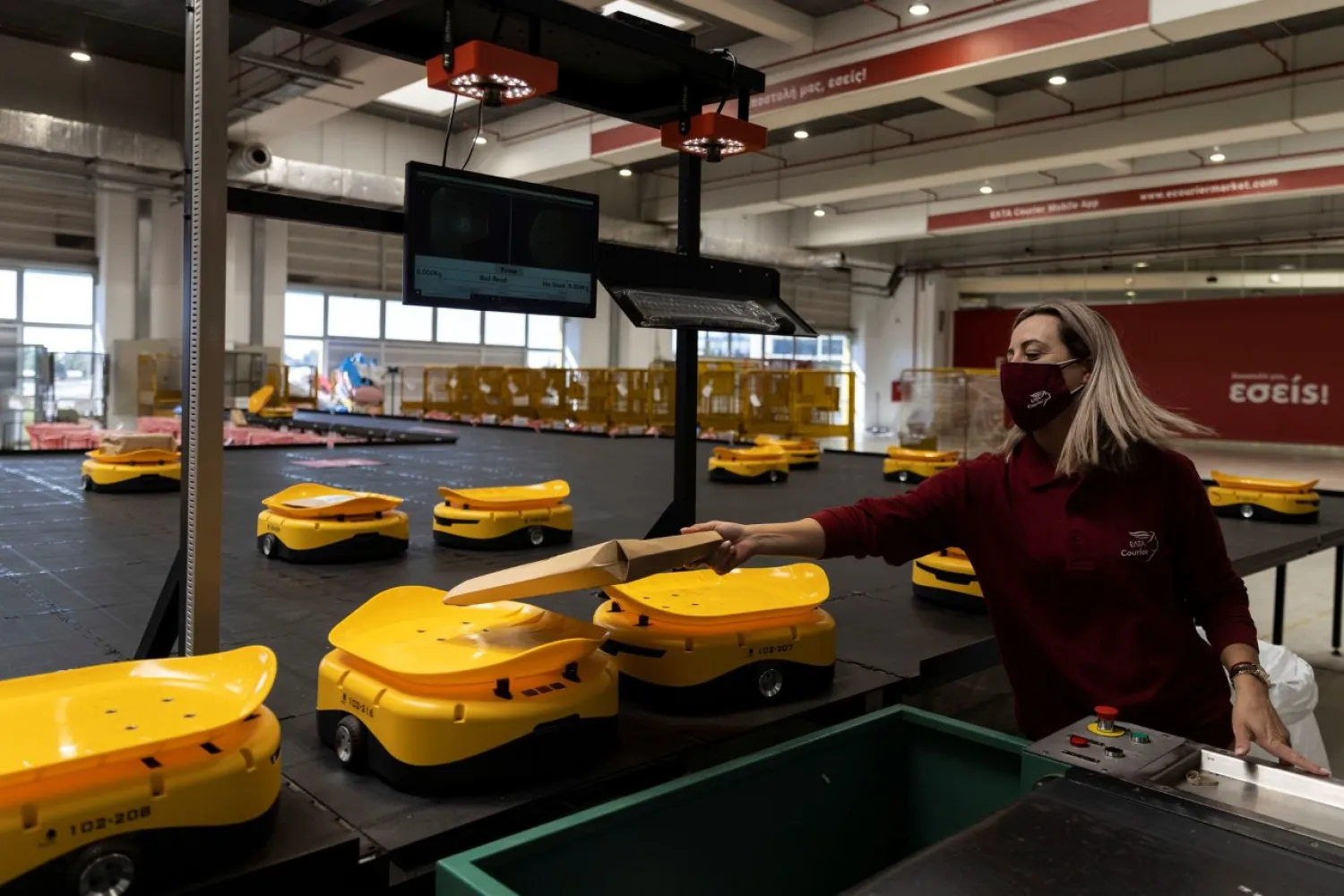 An employee places a parcel on a robot at the Hellenic Post's sorting center in Kryoneri, Greece, October 4, 2021. REUTERS/Alkis Konstantinidis