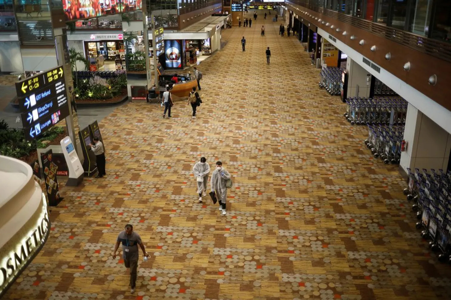 People, some of them wearing protective face masks, walk at Singapore's Changi Airport, following the outbreak of the coronavirus disease (COVID-19) March 30, 2020. REUTERS/Edgar Su

