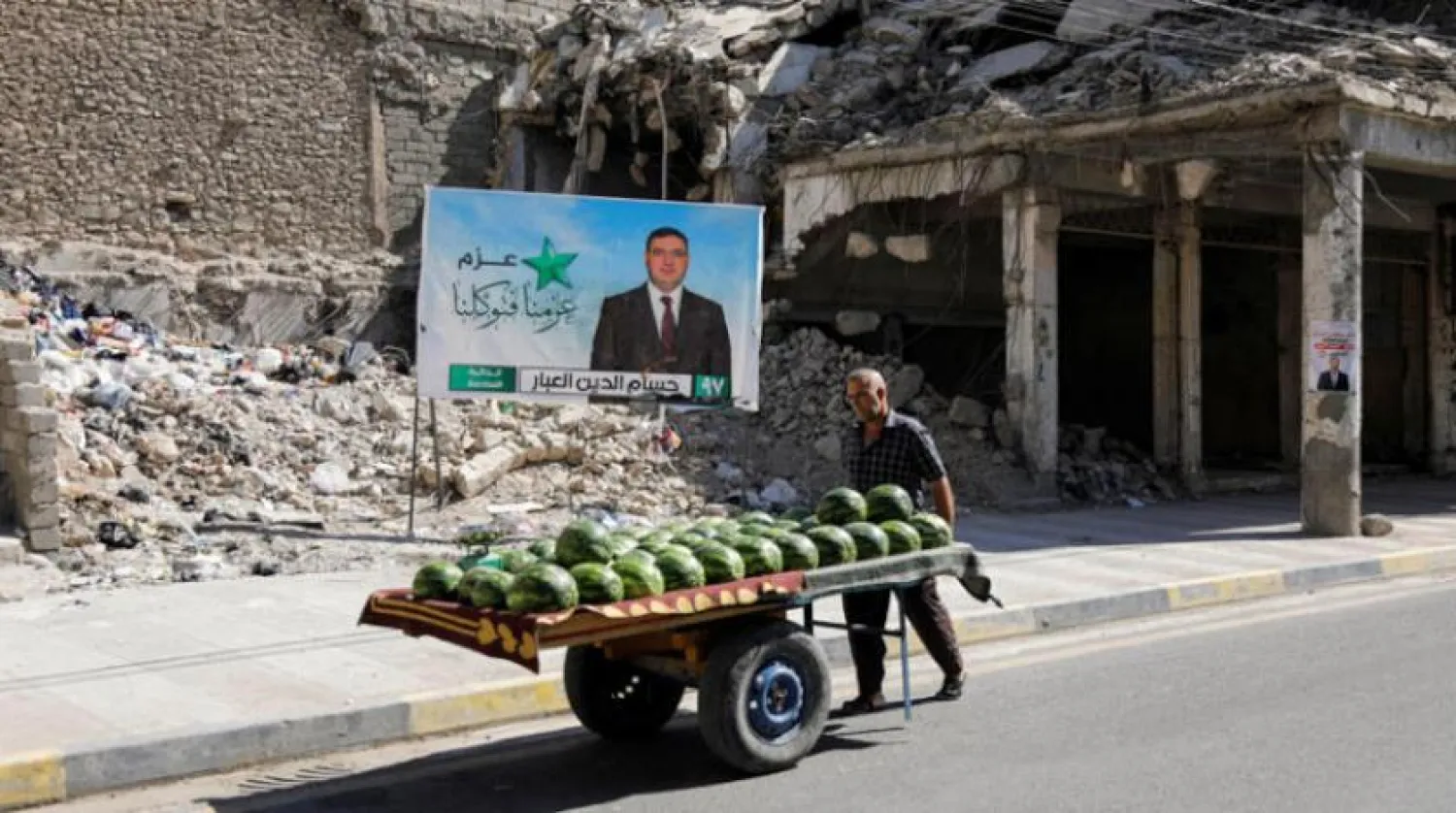 Musul'da yıkılan binalar arasında bir seçim afişi (Reuters)