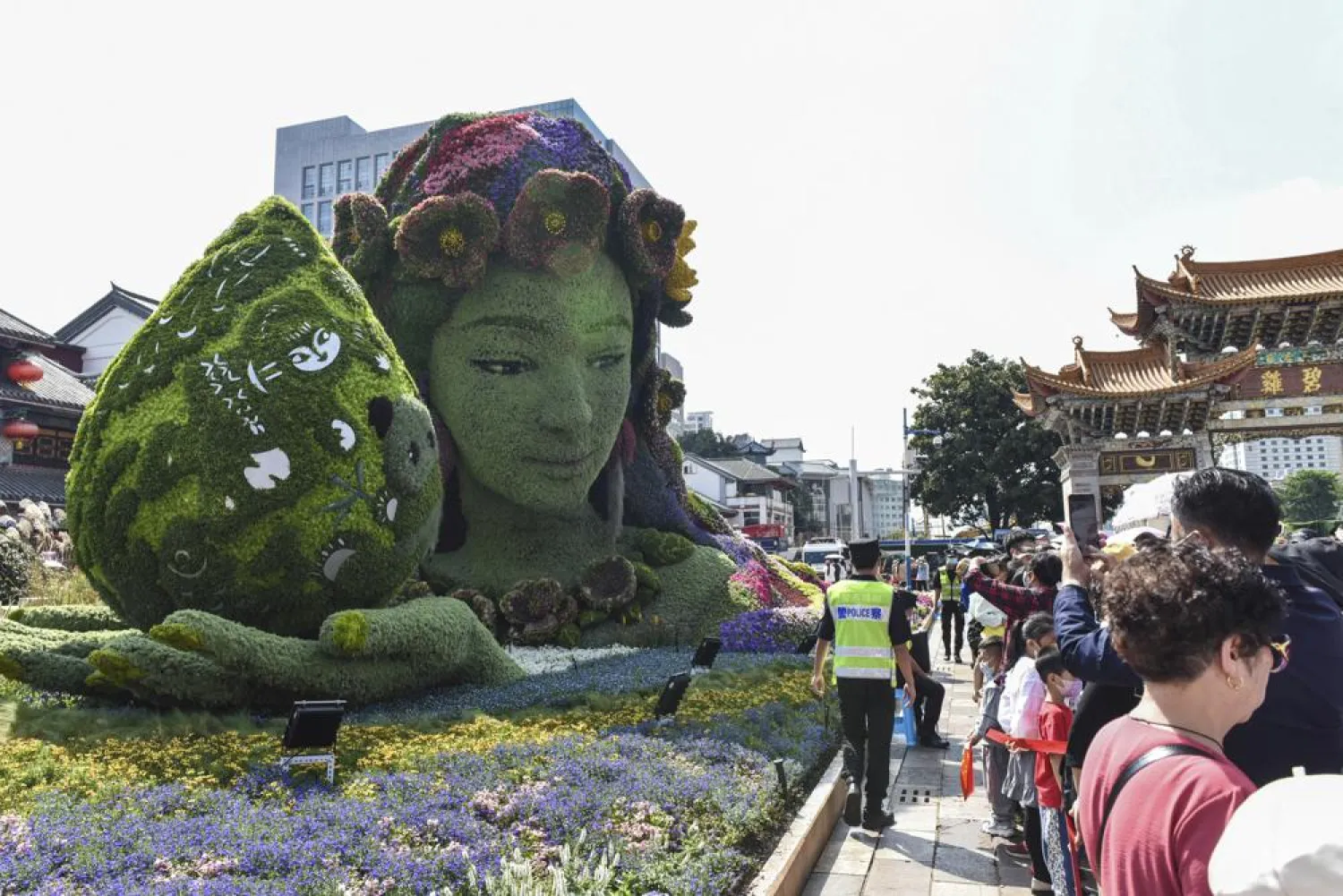 Tourists pass by a floral decoration celebrating the UN Biodiversity Conference (COP 15) in a park in Kunming, the host city, in southwestern China's Yunnan province, on Oct. 2, 2021. (Chinatopix via AP)
