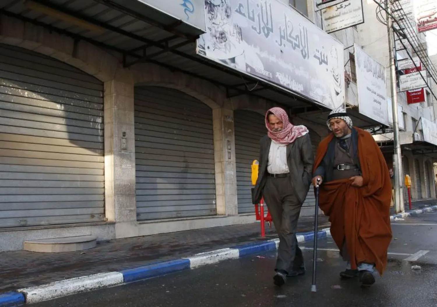 Palestinian men walk past closed shops in the West Bank city of Hebron. (AFP file photo)