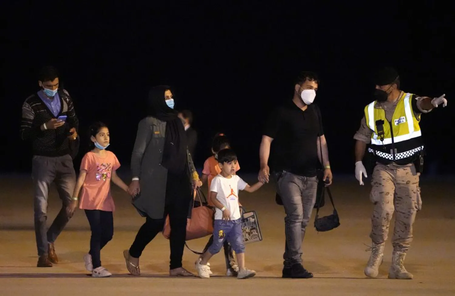 Afghan people who were transported from Islamabad, walk after disembarking a plane, at the Torrejon military base in Spain on Monday, Oct. 11, 2021. (AP Photo/Manu Fernandez)
