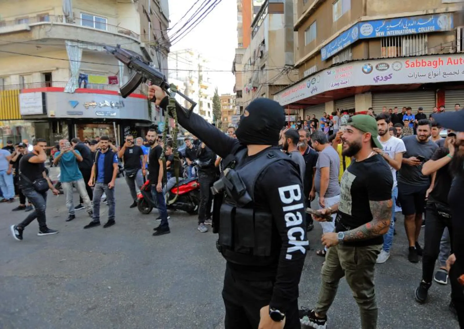 مسلّح من «حزب الله» يطلق النار خلال تشييع بعض ضحايا حادث الطيونة في الضاحية الجنوبية لبيروت (أ.ف.ب)