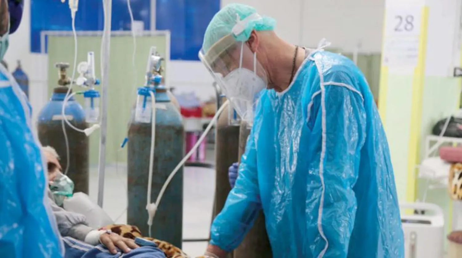 A medical staff member assists a patient suffering from the coronavirus disease inside a COVID-19 isolation ward in Qamishli. Asharq Al-Awsat