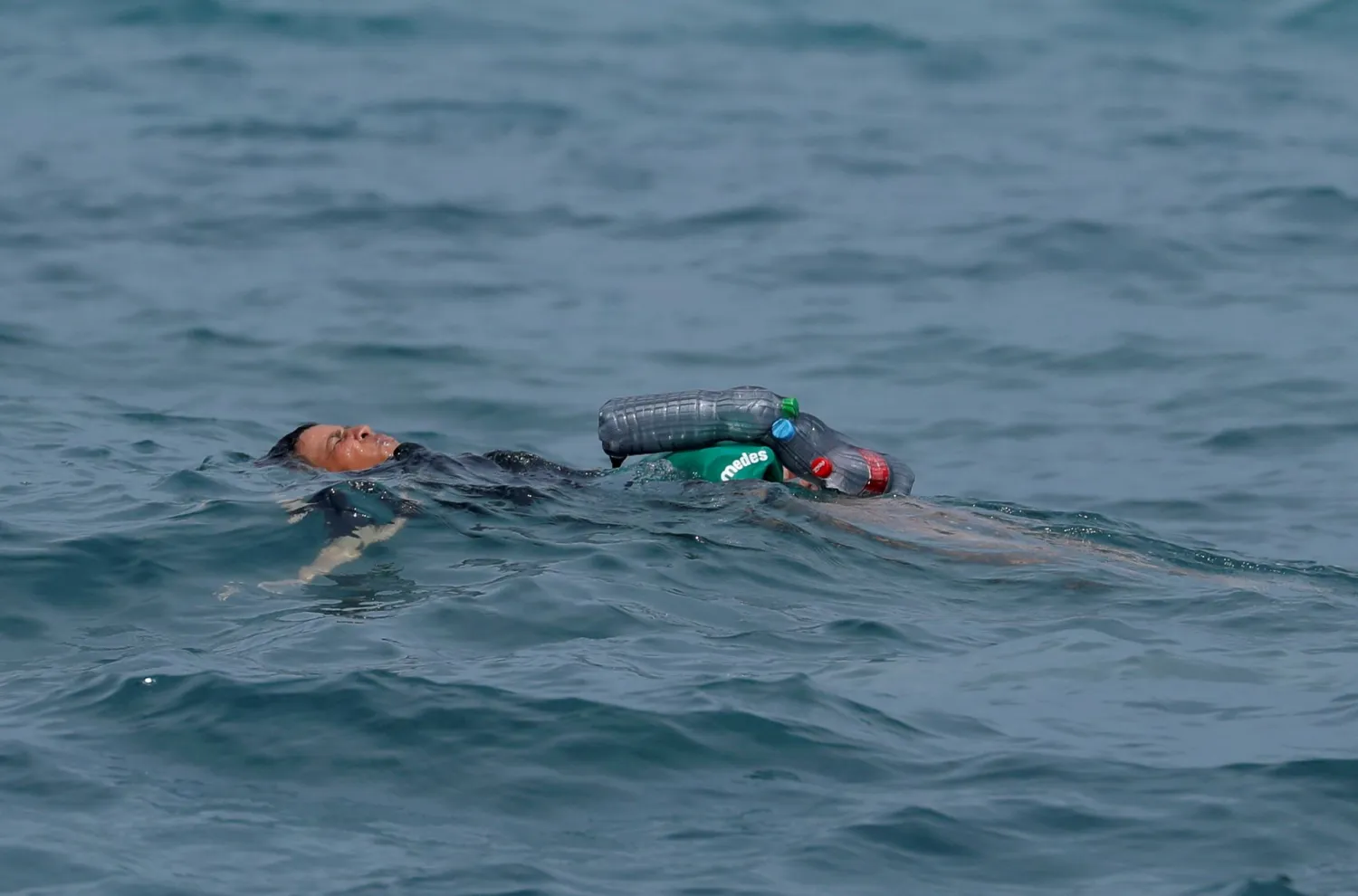 A Moroccan boy swims using bottles as a float, near the fence between the Spanish-Moroccan border, after thousands of migrants swam across the border, in Ceuta, Spain, May 19, 2021. REUTERS/Jon Nazca/File photo