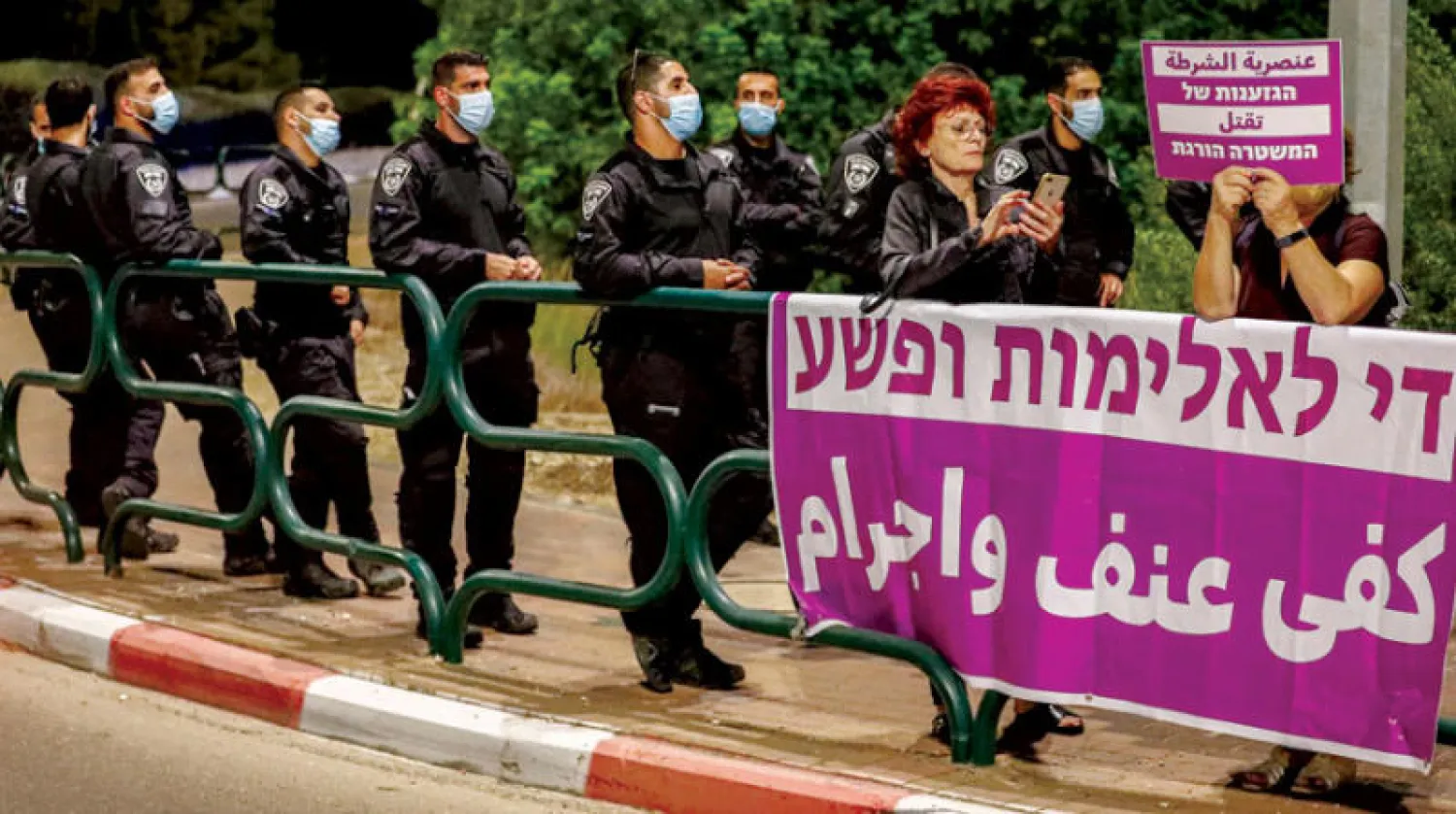 مظاهرة ترفع لافتات بالعربية والعبرية عن عنصرية الشرطة الإسرائيلية تجاه العنف داخل المنطقة العربية (أ.ف.ب)