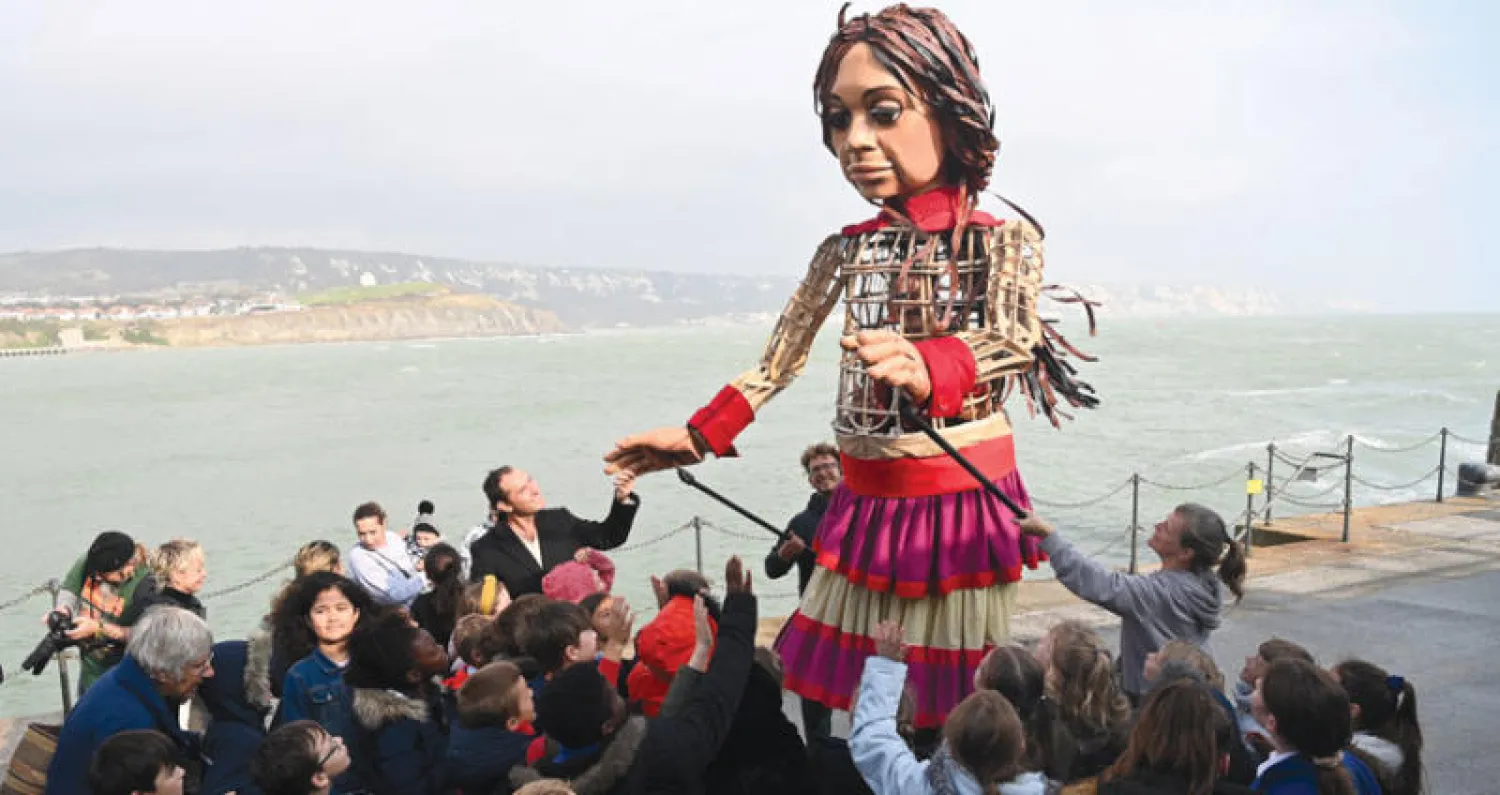 الممثل البريطاني جود لو في استقبال الدمية العملاقة «أمل الصغيرة» التي وصلت أمس إلى ميناء فولكستون الإنجليزي في نهاية رحلة بدأت من تركيا وقطعت فيها ثمانية آلاف كيلومتر لتجسيد معاناة اللاجئين السوريين (إ.ب.أ)