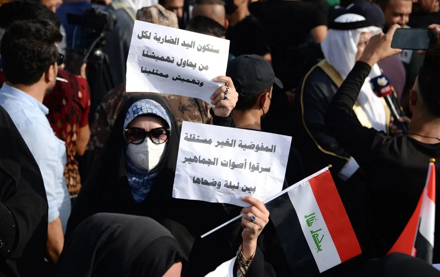 An Iraqi woman holds a sign accusing the electoral commission of stealing votes at a protest of Popular Mobilization Supports supporters in Mosul on October 14, 2021. (AFP)
