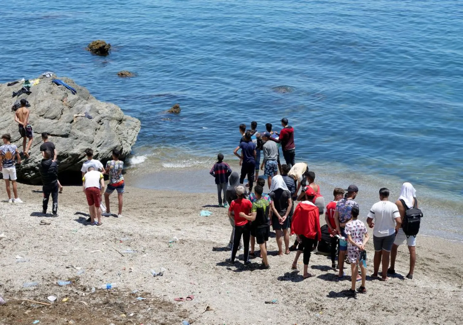 Migrants stand on the beach in Fnideq, close to the Spanish enclave Ceuta, in Morocco, May 19, 2021. REUTERS/Shereen Talaat/File Photo