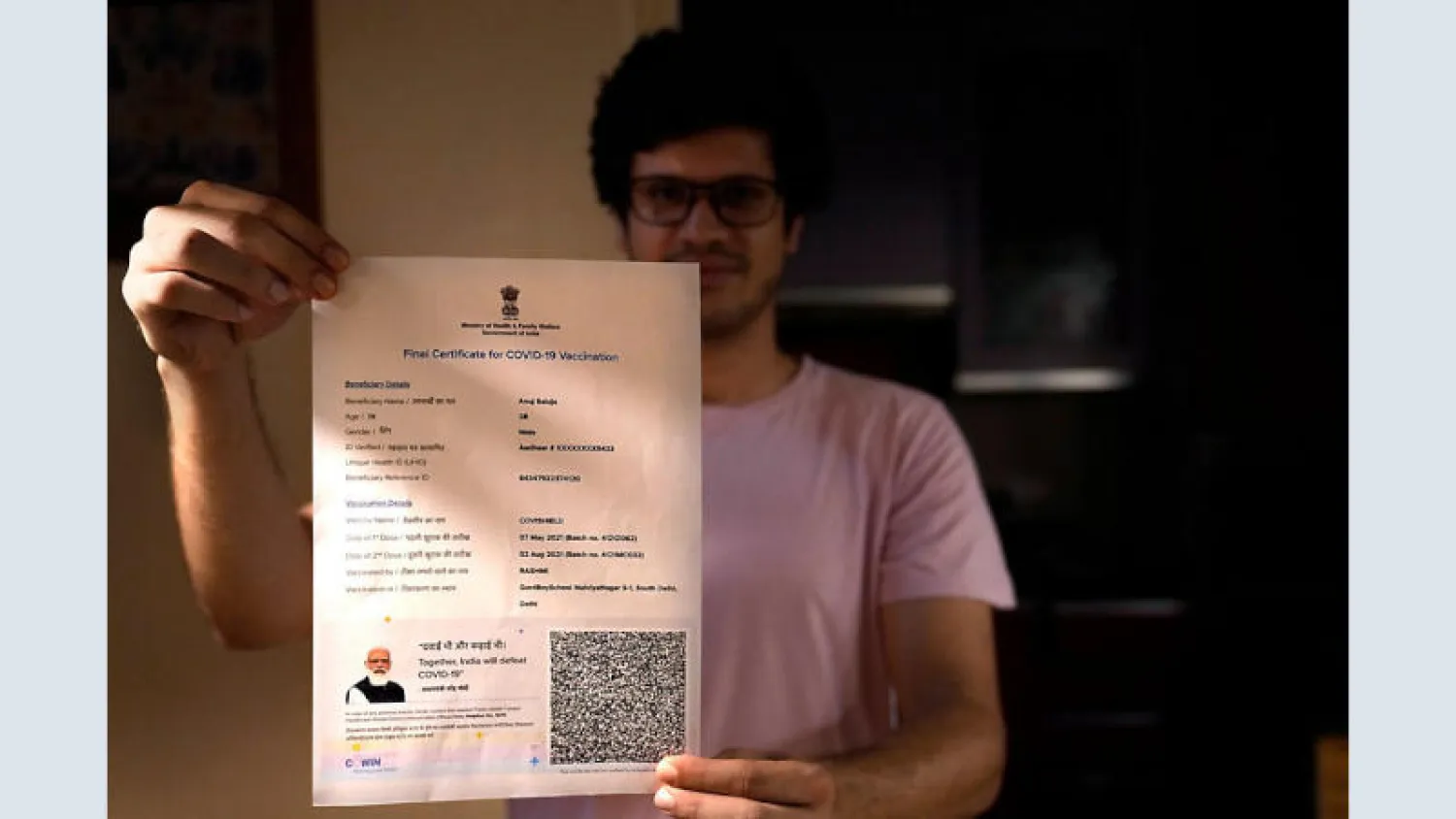 شخص يحمل شهادة اللقاح بصورة رئيس الوزراء الهندي (أ.ب)
