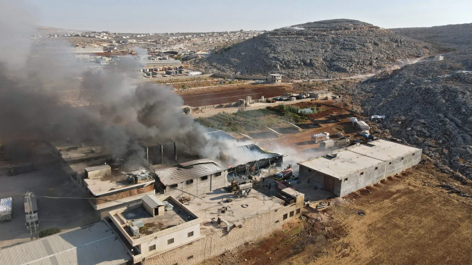 An aerial view shows smoke billowing from a warehouse after reported shelling on the town of Sarmada in Idlib province, northwestern Syria, Oct. 16, 2021. (AFP Photo)
