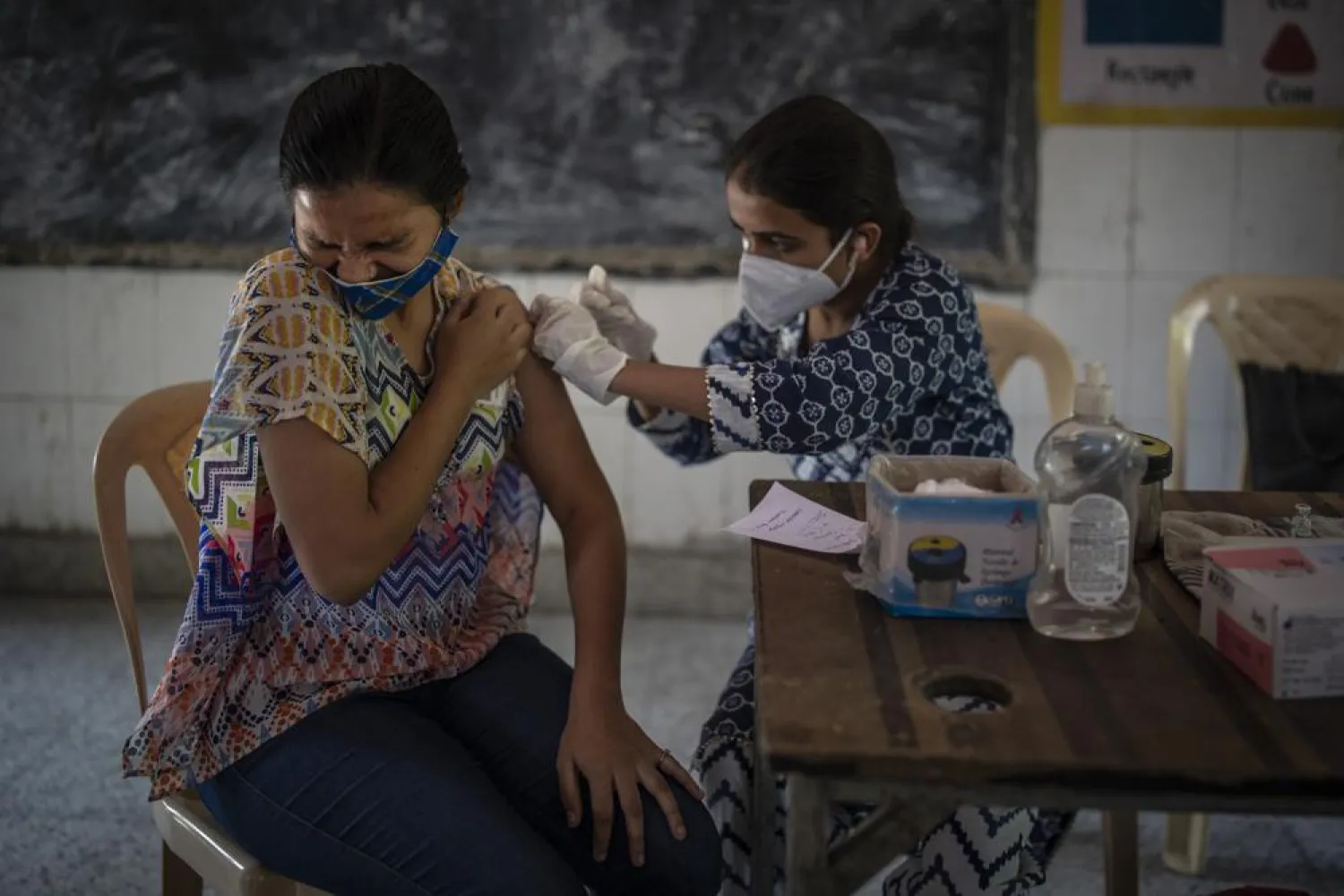 A woman reacts as a health worker inoculates her during a vaccination drive against coronavirus inside a school in New Delhi, India, Wednesday, Oct. 20, 2021. India is nearing a milestone of administering a total of one billion doses against COVID-19. (AP Photo/Altaf Qadri)
