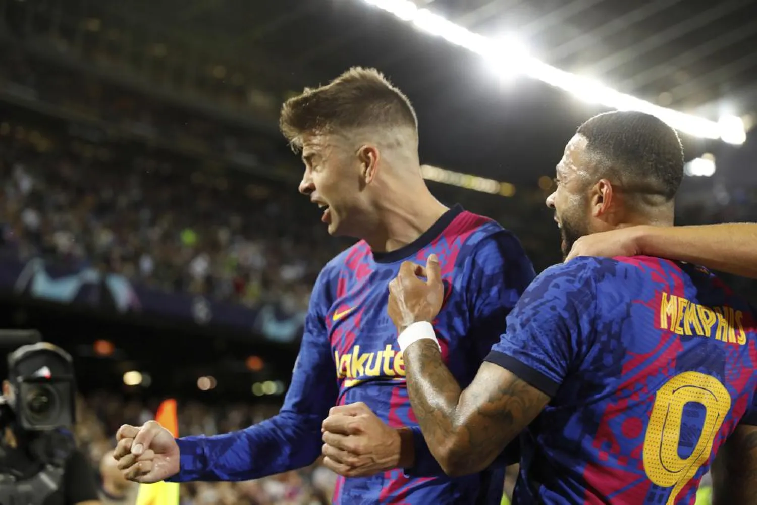 Barcelona's Gerard Pique, right, celebrates with his teammate Memphis Depay after scoring his side's first goal during a Champions League group E soccer match between F.C. Barcelona and Dinamo Kyiv at Camp Nou stadium in Barcelona, Spain, Wednesday, Oct. 20, 2021. (AP Photo/Joan Monfort)
