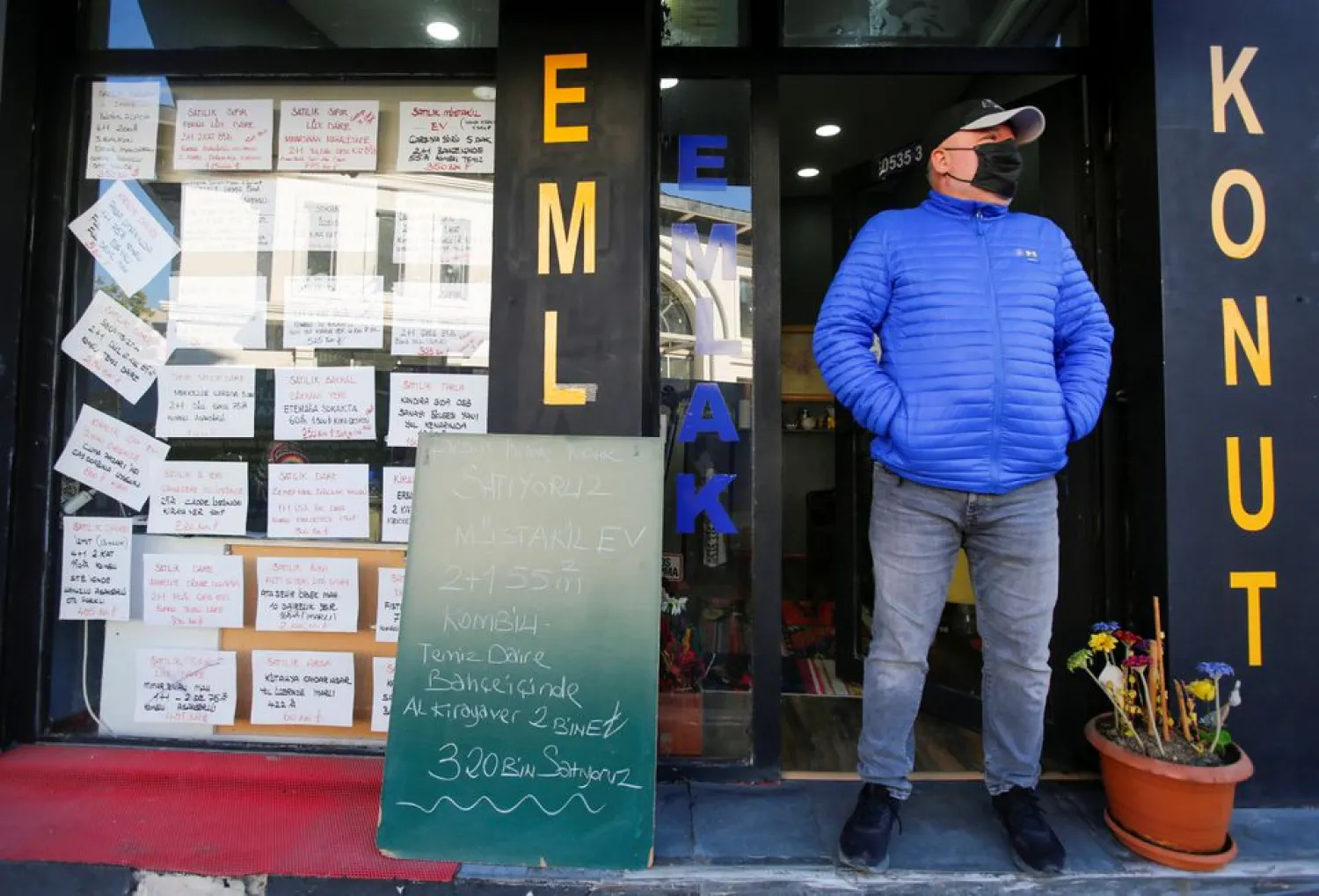 An estate agent stands at the entrance to his office as fliers of the houses for rent and sale are stuck on the window in Istanbul, Turkey October 22, 2021. (Reuters)