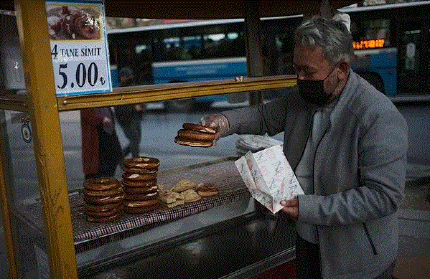A street vendor of simit, Turkey's ubiquitous pretzel-like snacks, prepares to serve a client, in Turkish capital, Ankara, Turkey, Thursday, Oct. 21, 2021. The Turkish lira plunged to a record low against the US dollar Thursday after a harsher than expected cut in interest rates.(AP Photo/Burhan Ozbilici)

