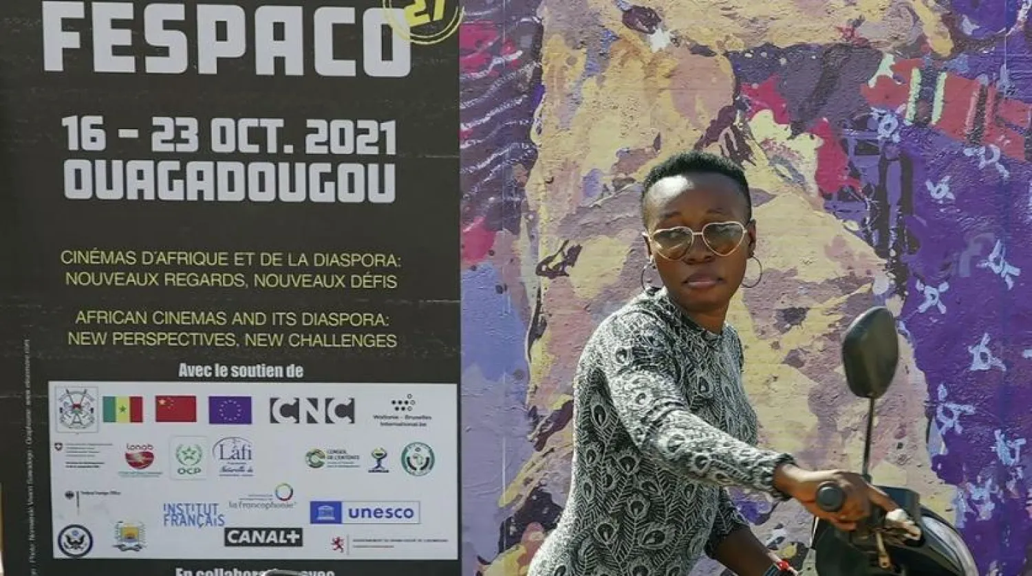 A woman pushes her scooter past the entrance of FESPACO (Pan-African Film & TV Festival of Ouagadougou) in Ouagadougou, Burkina Faso, Friday Oct. 15, 2021. (AP)
