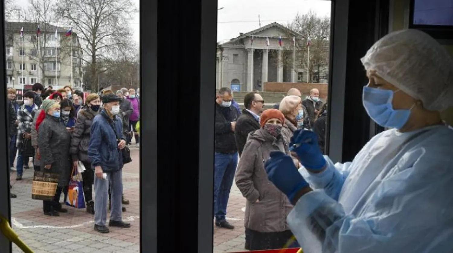 A Russian medical worker prepares a shot of Russia's Sputnik V coronavirus vaccine as people wearing face masks to protect against coronavirus queue to get a shot of Russia's Sputnik V coronavirus vaccine in a mobile vaccination center in Simferopol, Crimea, Tuesday, April 13, 2021. (AP Photo/Alexander Polegenko)
