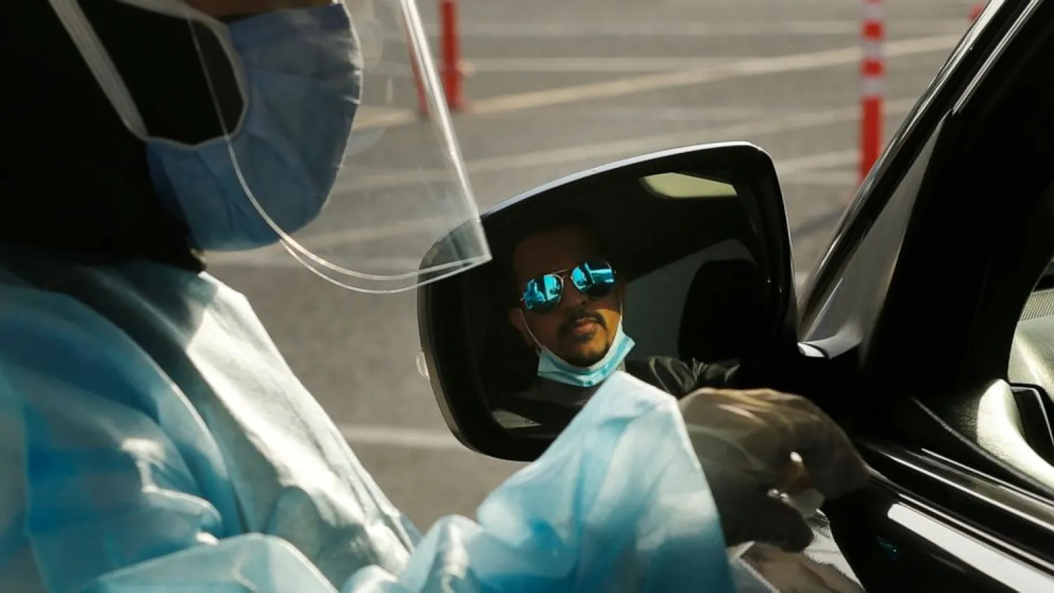 A Saudi health worker prepares to collect a swab sample for PCR test at the drive-through testing center at King Abdulaziz University. (AP)