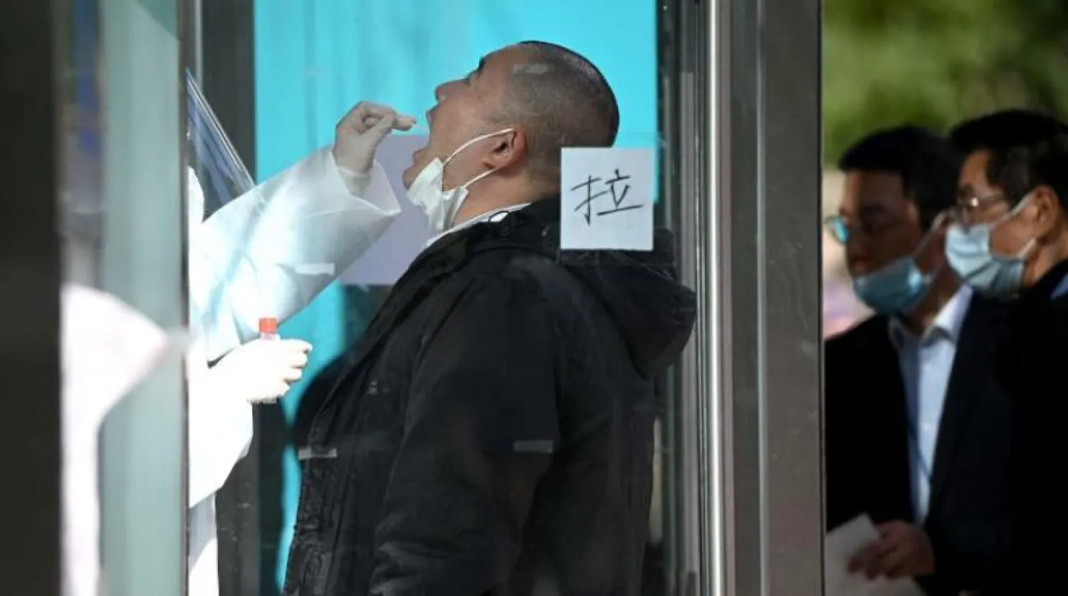 Pekin’de bir sağlık çalışanı sürüntü örneği alıyor (AFP)