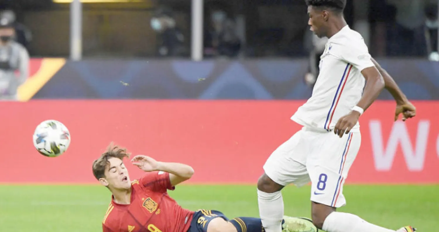 تشواميني (يمين) يستخلص الكرة من الإسباني جافي في نهائي دوري الأمم الأوروبية (رويترز)