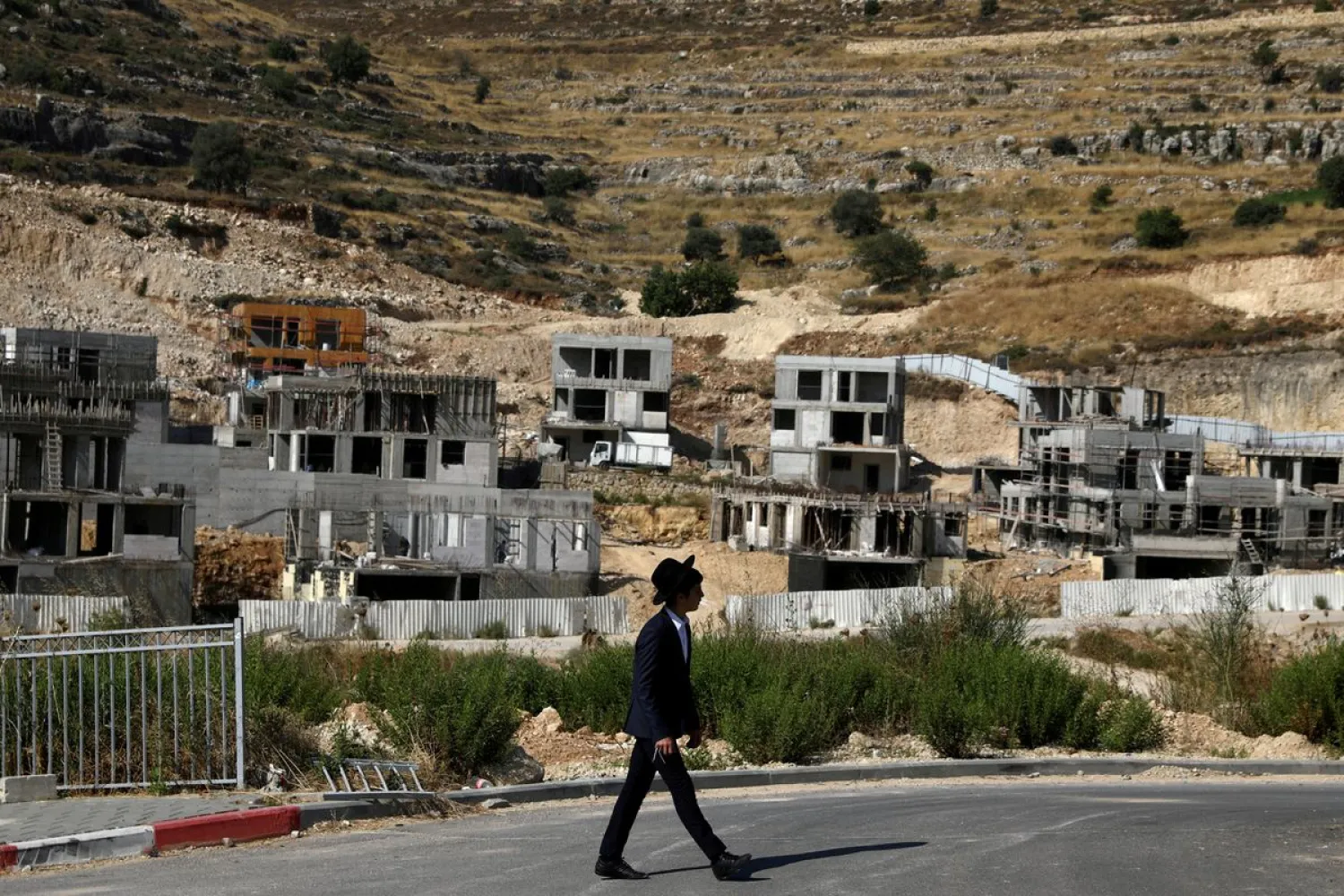 A Jewish settler walks past Israeli settlement construction sites around Givat Zeev and Ramat Givat Zeev in the Israeli-occupied West Bank, near Jerusalem June 30, 2020. REUTERS/Ammar Awad/File Photo