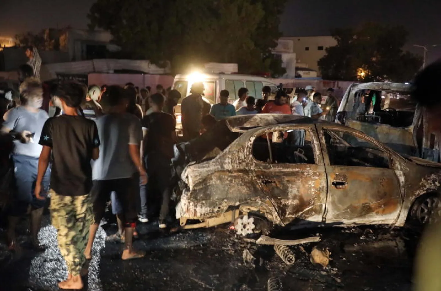 يمنيون يتفقدون موقع التفجير خارج مطار عدن (إ.ب.أ)