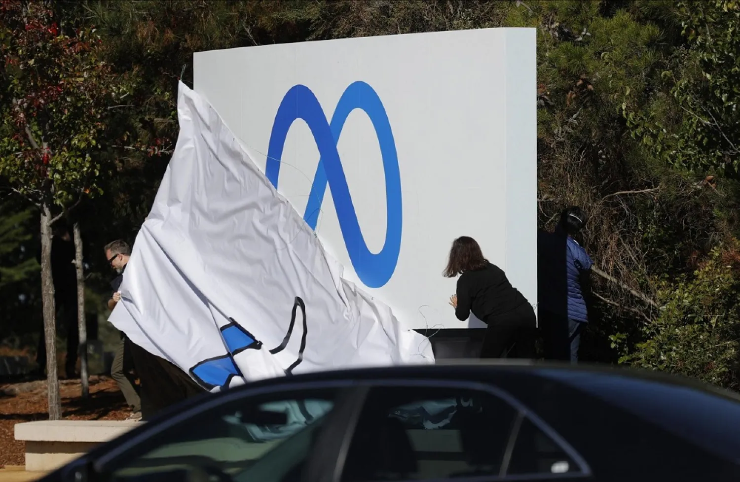 Facebook employees unveil a new logo and the name "Meta" on the sign in front of Facebook headquarters on October 28, 2021 in Menlo Park, California. (AFP)