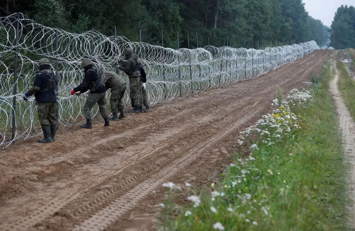 Polish soldiers build a fence on the border between Poland and Belarus near the village of Nomiki, Poland August 26, 2021. REUTERS/Kacper Pempel/File Photo