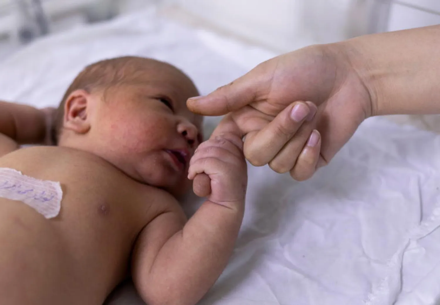 طفل حديث الولادة يمسك بيد ممرضة في مستشفى بكابل (رويترز)