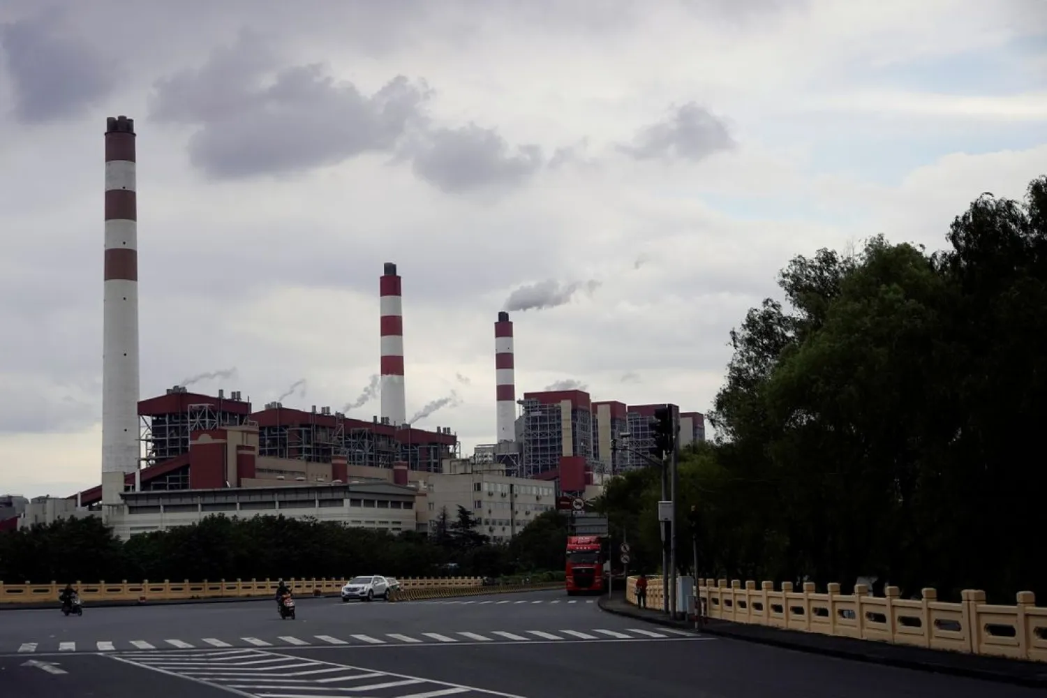 People drive past a coal-fired power plant in Shanghai, China October 21, 2021. (Reuters)
