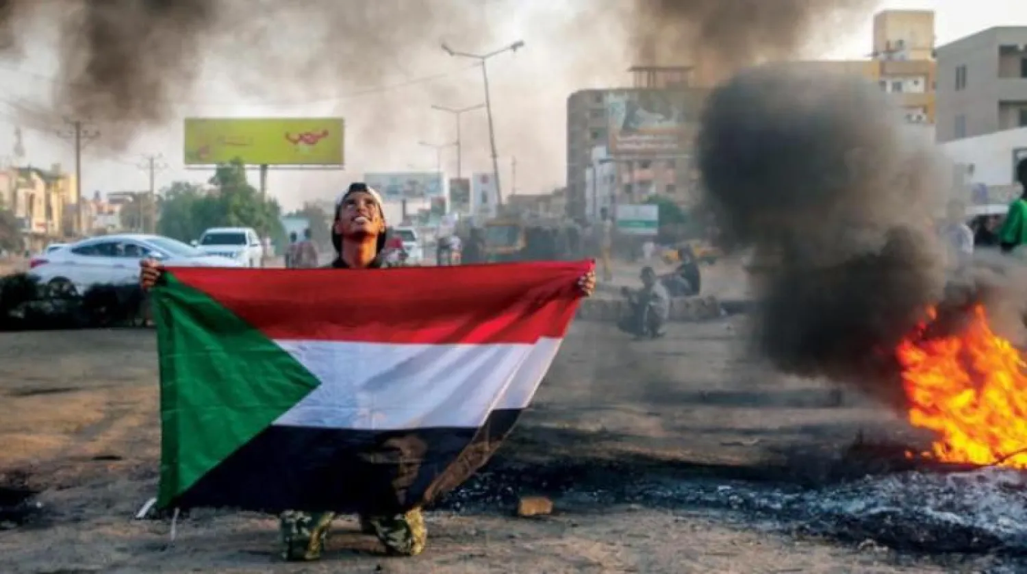متظاهر سوداني يحمل علم بلاده خلال احتجاجات على إجراءات الجيش في الخرطوم (إ.ب.أ)