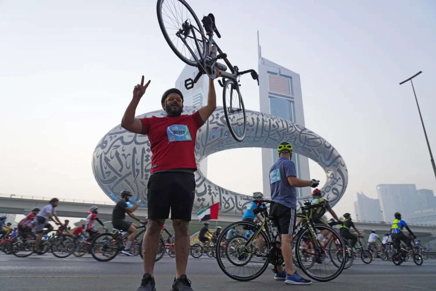 A bicyclist poses for a photograph in front of the Museum of the Future and Emirates Towers in Dubai, United Arab Emirates, Friday, Nov. 5, 2021. (AP Photo/Jon Gambrell)
