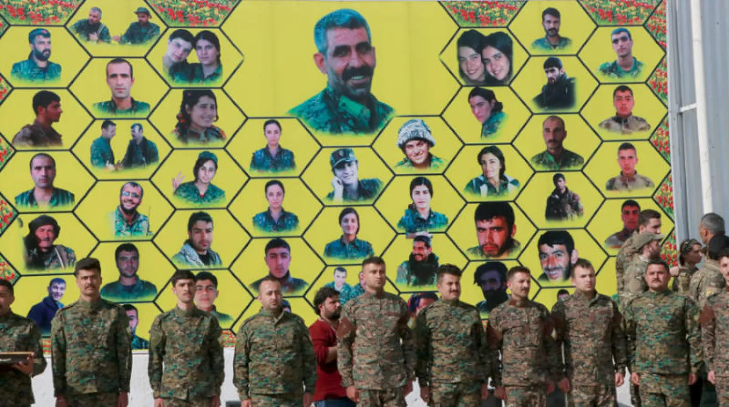 مقاتلون أكراد وراء لافتة عليها صور قتلاهم خلال معارك ضد «داعش» (الشرق الأوسط)